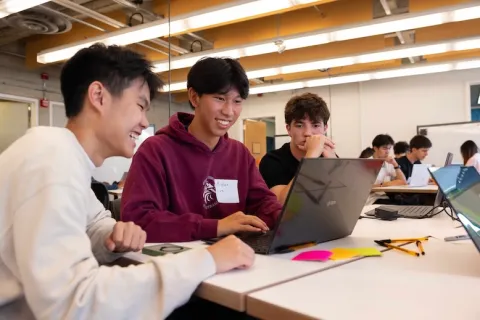 Three students working together on a laptop