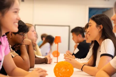 Close up of two rows of people sitting face-to-face and talking to eachother.